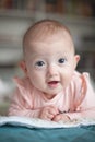 Portrait of a charming baby lying on its stomach and laughing. Family morning at home. Tummy time