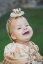 Charming baby in princess costume with a crown on head is laughs