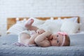 Adorable baby boy in white sunny bedroom plays alone on the bed. Royalty Free Stock Photo