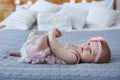Adorable baby boy in white sunny bedroom plays alone on the bed. Royalty Free Stock Photo