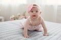 Adorable baby boy in white sunny bedroom plays alone on the bed. Royalty Free Stock Photo