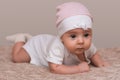 Charming beautiful lovely small female baby with plump cheeks creeps on bed, looks innocently on something, being naughty. Cute ba Royalty Free Stock Photo