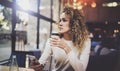 Charming beautiful young woman reading email message on mobile phone during rest time in coffee shop. Bokeh and flares Royalty Free Stock Photo