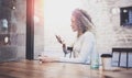 Charming beautiful young woman reading email message on mobile phone during rest time in coffee shop. Bokeh and flares Royalty Free Stock Photo