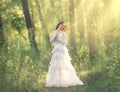 Charming beauty with dark hair standing in light forest, goddess and fairy of morning sun in warm rays, sweet girl in