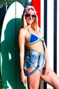 Charming blond girl surfer wearing sunglasses posing in summer with surf Royalty Free Stock Photo