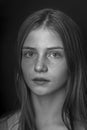 Beautiful young girl with freckles indoors on a black background, close up portrait. Black and white Royalty Free Stock Photo