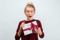 Charming blonde girl with gift posing with surprised face expression. Studio shot white background, isolated Royalty Free Stock Photo