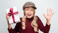 Charming blonde girl with gift posing with surprised face expression. Studio shot white background, isolated Royalty Free Stock Photo