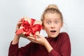 Charming blonde girl with gift posing with surprised face expression. Studio shot white background, isolated Royalty Free Stock Photo