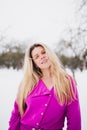 Charming blonde with long hair and in a coat in a slanted park in winter