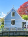 A charming blue house with a white picket fence nestled in a serene environment, exuding a sense of tranquility and