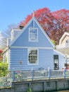 A charming blue house with a white picket fence standing peacefully under a clear blue sky, radiating warmth and comfort
