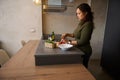 Charming body positive young woman standing at kitchen table, sorting ingredients while cooking healthy dinner at home Royalty Free Stock Photo