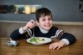 Charming boy smiles looking at camera while enjoying a healthy vegan lunch in the reastaurantof the departure terminal of an Royalty Free Stock Photo