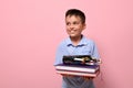 A charming boy, a student at school, holds books in front of him and pencil case with pens, felt-tip pens and markers falling out Royalty Free Stock Photo