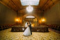 Charming bride dancing with handsome elegant groom near old wooden baluster on the background of luxury interior