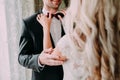 Charming bride fixes ornamented red bow tie on groom`s neck. Wedding.