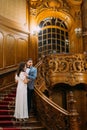 Charming bride and handsome elegant groom embracing on old stairs with the background of gorgeous wooden vintage Royalty Free Stock Photo