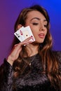 Brunette woman in black velvet dress showing two playing cards, posing against coloful background. Gambling Royalty Free Stock Photo