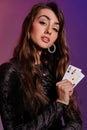 Brunette woman in black velvet dress showing two playing cards, posing against coloful background. Gambling Royalty Free Stock Photo