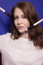 Charming brunette woman in white t-shirt with makeup brushes isolated on colorful blue background. professional makeup artist Royalty Free Stock Photo