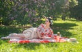 A charming brunette young girl enjoys a rest and a picnic on the green summer grass alone. pretty woman have a holiday and spend v Royalty Free Stock Photo