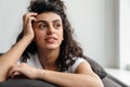 Charming brunette young woman looking aside while resting on sofa