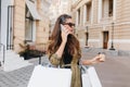 Charming businesswoman talking on phone while doing shopping. Outdoor photo of serious brunette fashionista lady Royalty Free Stock Photo