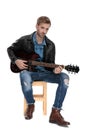 Seated man playing the guitar and looking ahead Royalty Free Stock Photo