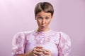 Charming caucasian girl with short haircut drinking with winding straw from a transparent glass. Grey eyes, puffy pink Royalty Free Stock Photo