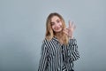 Charming caucasian woman looking at camera, smiling, doing okay gesture