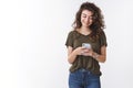 Charming cheerful georgian young curly-haired woman holding smartphone reading message look phone display smiling