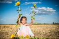 Charming cheerful little girl sitting on the field Royalty Free Stock Photo