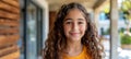 Charming child with curly hair beaming a radiant smile while gazing directly at the camera