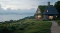 A charming cottage with a grass-covered roof glows warmly at night, nestled on a cliff by the ocean, inviting Royalty Free Stock Photo