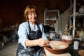 Nice old woman ceramist painting clay bowl in workshop Royalty Free Stock Photo