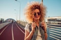 Charming curly blonde listen to music. Young woman with big headphones. outdoors portrait of trendy girl Royalty Free Stock Photo