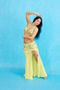 Charming dancer performs oriental belly dance on a blue background.