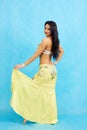 Charming dancer performs oriental belly dance on a blue background.
