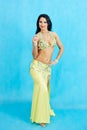 Charming dancer performs oriental belly dance on a blue background.