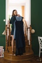 Young woman holding dresses on hanger, trying to decide what to wear.