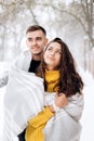 Charming dark-haired girl dressed in a yellow sweater and her boyfriend wrapped together in a gray scarf are standing in Royalty Free Stock Photo