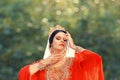 Charming delightful Turkish lady in bright red scarlet light dress puts her hands to a gorgeous face, mistress Roksolana