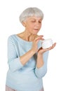 Charming elderly woman applying cosmetic cream on her face for facial skin care on a white background.