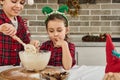 Charming European children cooking Christmas cookies together at home kitchen. Adorable boy kneads dough with a wooden spoon when Royalty Free Stock Photo