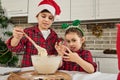 Charming European children having fun together, preparing dough for Christmas cookies, gingerbread, muffins in the home kitchen. Royalty Free Stock Photo