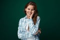 Charming European woman wearing a plaid shirt and jeans on a green studio background