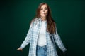 Charming European woman wearing a plaid shirt and jeans on a green studio background