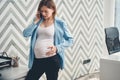 Upset pregnant woman talking on cellphone in office Royalty Free Stock Photo